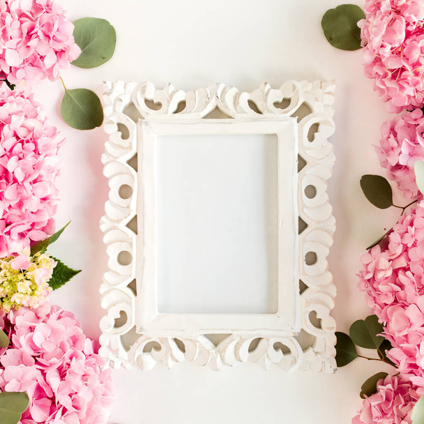 Carved, white frame decorated of pink hydrangea flowers on white background. Floral concept. Flat lay, top view.  - Fotoğraf, Görsel