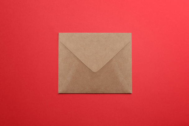 Brown paper envelope on red background, top view - Фото, изображение