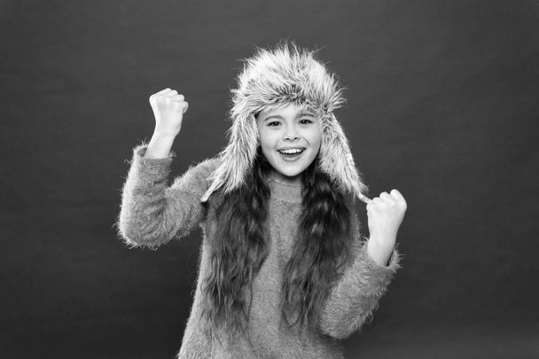 Fashion model wear fur hat red background. warm kid fashion. seasonal health care. holiday activity outdoor. happy little girl in earflap hat. small child ready for winter. ready for having fun - Valokuva, kuva