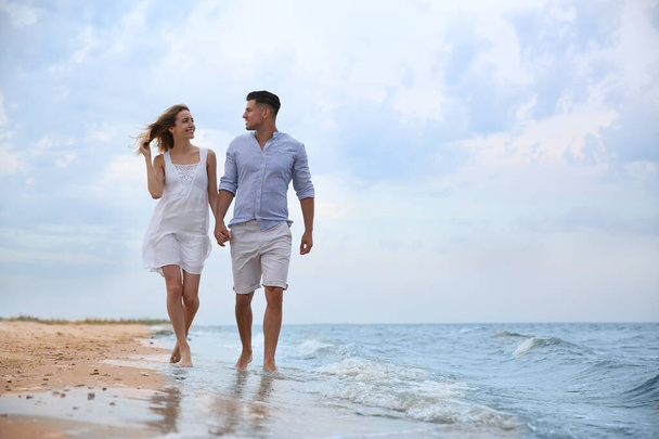 Ευτυχισμένο ζευγάρι που κάνει ρομαντική βόλτα στην παραλία. Χώρος για κείμενο - Φωτογραφία, εικόνα
