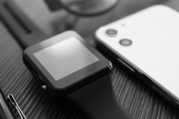 Stylish smart watch and phone on black table, closeup - Valokuva, kuva