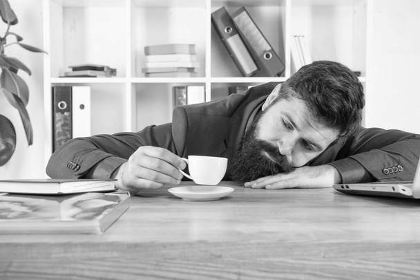 Hard morning. Bearded hipster formal suit relaxing with coffee. Office life. First coffee. Sleepless night. Procrastination is thief of time. Man handsome boss sleep in office drinking coffee - Photo, Image