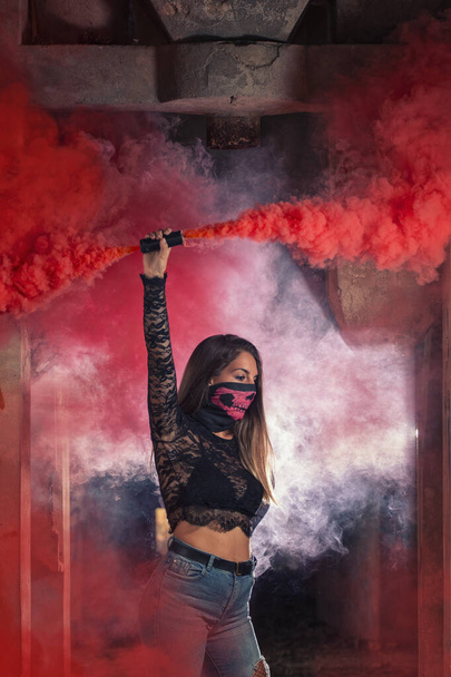 Gefährliches Mädchen mit pinkfarbener Mundmaske in einer verlassenen Fabrik mit einer Rauchgranate. - Foto, Bild