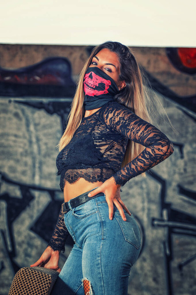 Gefährliches Mädchen mit pinkfarbener Mundmaske auf einem alten Sofa in einer verlassenen Fabrik. - Foto, Bild