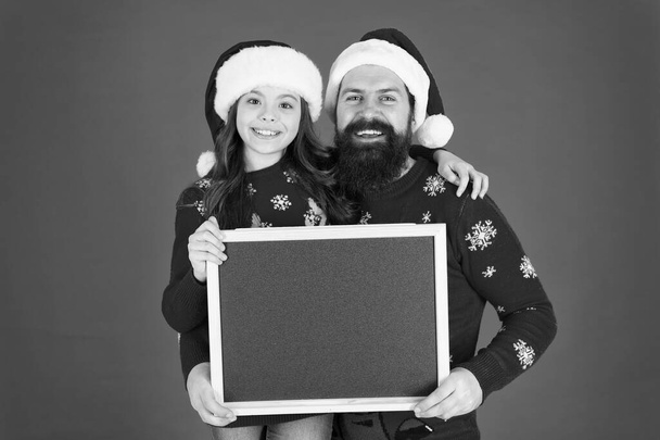 Christmas celebration schedule. Christmas party timing. Christmas check list. Father daughter with blackboard copy space. Get ready for holiday. Santa claus family look. Bearded dad and small girl - Zdjęcie, obraz