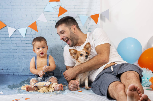 Dad playing with son on party for one year baby boy with a set composed of brick wallpaper. - Φωτογραφία, εικόνα