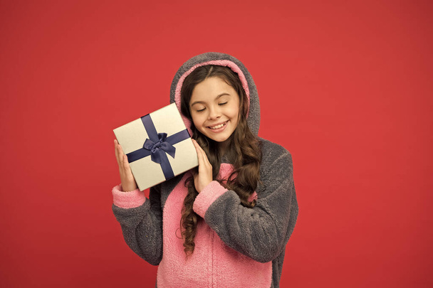 Spring holidays. Girl in bunny pajamas. Child in rabbit kigurumi. Happy girl in cute pajamas. Lifestyle concept. Rest and relax. Child in pajamas hold wrapped gift box. Shop and shopping concept - Photo, Image
