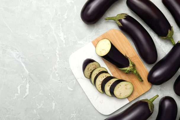 Cut and whole raw ripe eggplants on grey table, flat lay. Space for text - Φωτογραφία, εικόνα