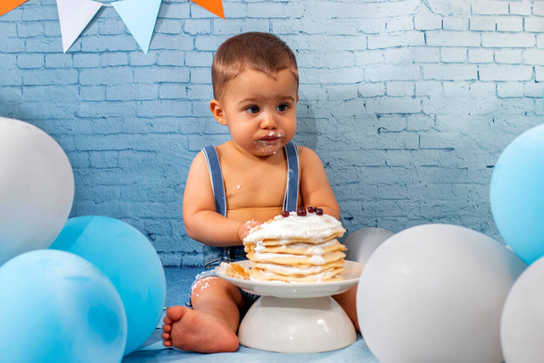 Fête pour bébé garçon d'un an avec un ensemble composé de ballons, rubans, papier peint et crêpes en brique. - Photo, image