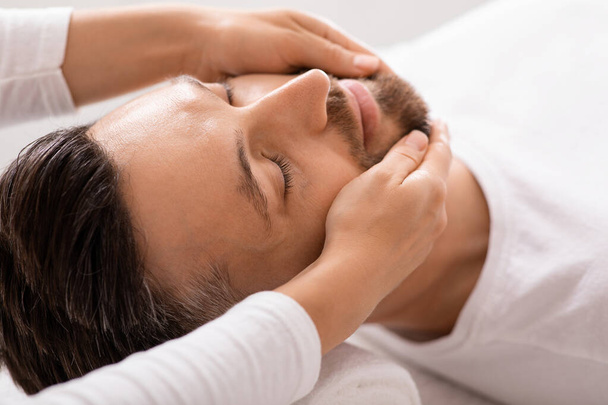Primo piano di uomo ottenere massaggio viso guarigione al centro benessere - Foto, immagini