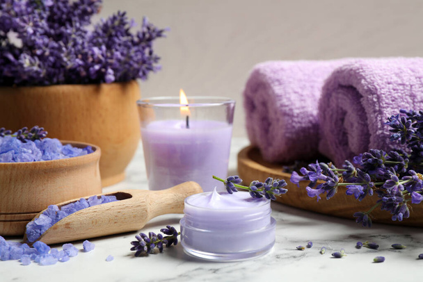 Cosmetic products and lavender flowers on white marble table - Photo, image