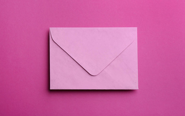 Pink paper envelope on purple background, top view - Φωτογραφία, εικόνα
