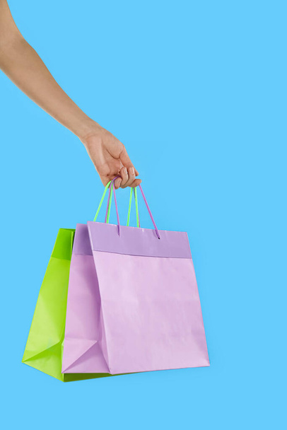 Woman with paper shopping bags on light blue background, closeup - Foto, Imagem
