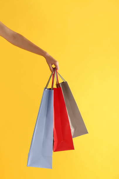 Woman with paper shopping bags on yellow background, closeup - Foto, immagini