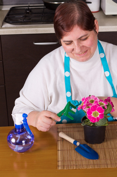 Mujer de mediana edad cuidando de la flor
 - Foto, imagen