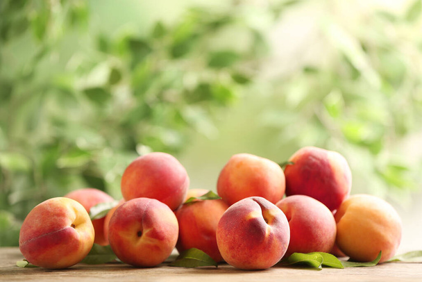 Fresh sweet peaches on wooden table outdoors - Fotoğraf, Görsel