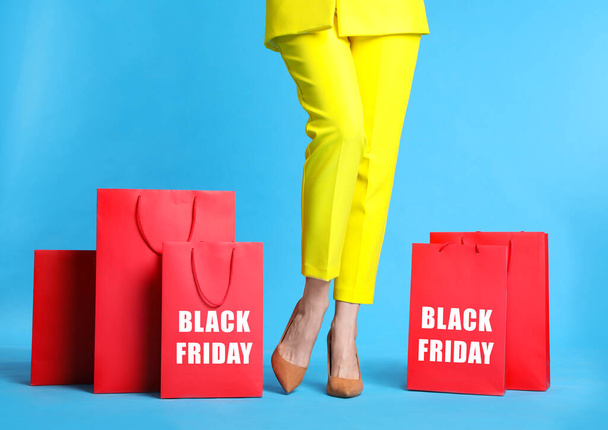 Woman with shopping bags on light blue background, closeup. Black Friday - Foto, Imagen
