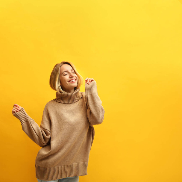 Beautiful young woman wearing knitted sweater on yellow background. Space for text - Fotografie, Obrázek