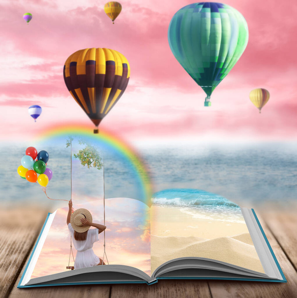Fantasy worlds in fairytales. Book, hot air balloons and pink sky over misty sea on background - Valokuva, kuva