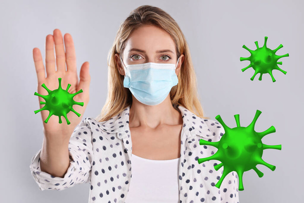 Stop Covid-19 outbreak. Woman wearing medical mask surrounded by virus on light background - Fotoğraf, Görsel