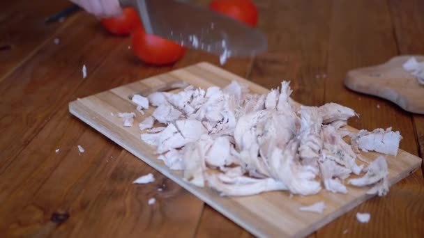 Een vrouw hand zwaait een mes sterk en koteletten gekookt vlees op een houten plank. - Video