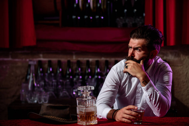 Handsome bearded man looking tired and upset drinking whiskey alone at the bar rubbing his forehead stress depression. Depressed unhappy exhausted. - Foto, Imagen