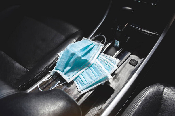 Medisch gezichtsmasker geplaatst op middenconsole in de auto, Coronavirus (COVID-19) preventie concept - Foto, afbeelding