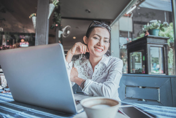 Pracující asijské žena sedí a šťastně se usmívá v kavárně.Zaměřte se na tvář - Fotografie, Obrázek