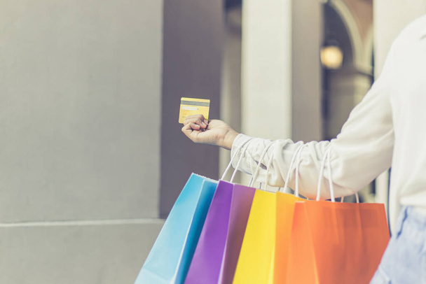 Las mujeres jóvenes llevan coloridas compras y utilizan su tarjeta de crédito para comprar en el centro comercial, el consumismo de las personas asiáticas que están felices de comprar productos. - Foto, Imagen