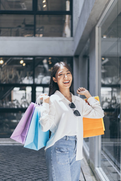 Młode Azjatki szczęśliwie nosić kolorowe torby na zakupy do sklepu w centrum handlowym lub centrum handlowym, Dzień wyprzedaży, Happy shopping concept.  - Zdjęcie, obraz
