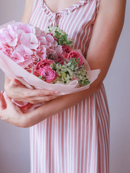 Fille dans une robe de soleil rose tient un bouquet vert rose dans ses mains - Photo, image