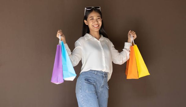 Casella di testo di input, sfondo marrone, Giovani donne che trasportano borse colorate della spesa, felice di acquistare il concetto di prodotti. - Foto, immagini