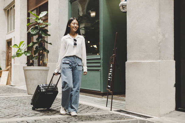 アジアの女性の休暇、トロリーバッグ、長い週末旅行、旅行、観光祭のコンセプトで旅行するスーツケース黒を運ぶビーミング. - 写真・画像