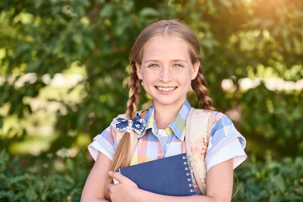 Beautiful american portrait of schoolgirl. Preschool kid holding book. Smiling - Foto, Imagen