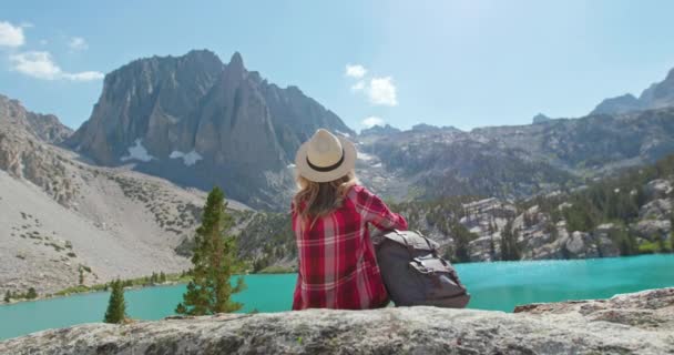 Vissza kilátás utazó lány ül festői tó és a hegyekre néző, 4K - Felvétel, videó