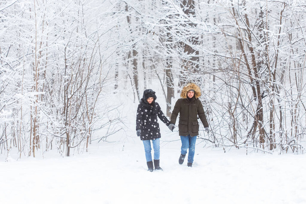 Fiatal pár sétál egy havas parkban. Téli szezon. - Fotó, kép