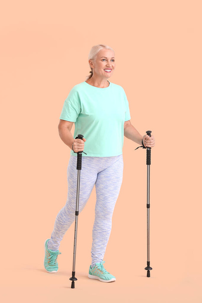 Mujer madura con bastones para caminar sobre fondo de color - Foto, Imagen
