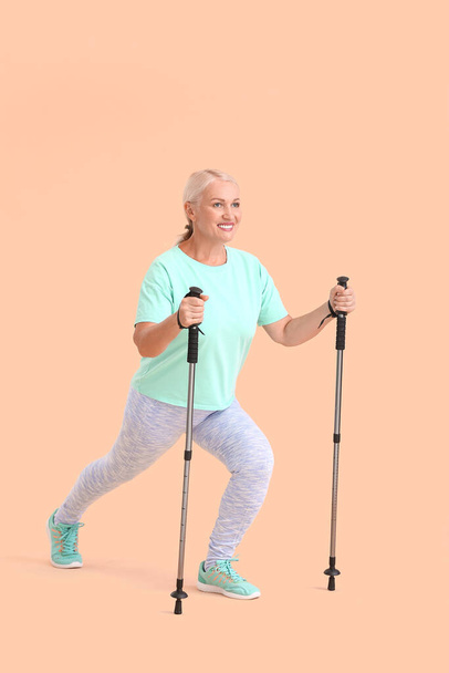 Mature woman with walking poles on color background - Foto, immagini