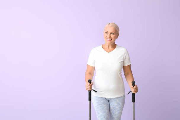 Ältere Frau mit Wanderstöcken auf farbigem Hintergrund - Foto, Bild