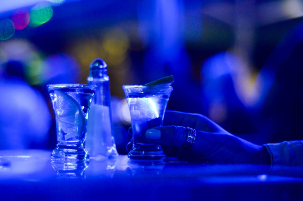 чашки текилы в баре с голубыми огнями ночного клуба  - Фото, изображение