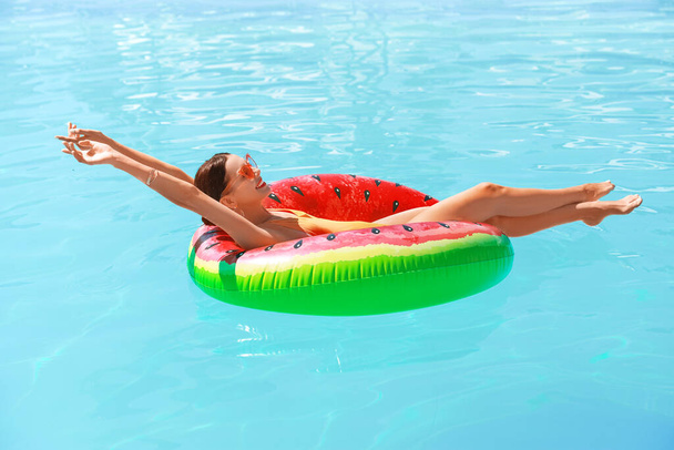 Όμορφη νεαρή γυναίκα χαλαρώνοντας στο δαχτυλίδι κολύμπι στην πισίνα - Φωτογραφία, εικόνα