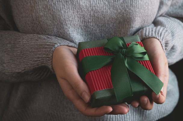 Frauenhände halten verpackten Geschenkkarton mit Schleife. Weihnachten oder Neujahr handgemachtes Geschenk. Nahaufnahme - Foto, Bild