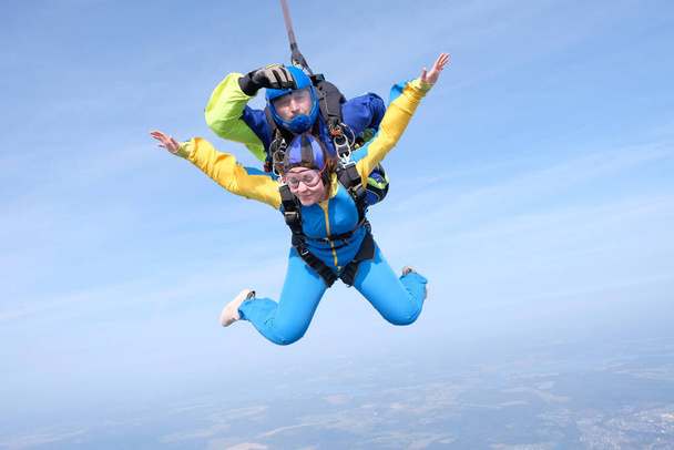 Hava dalışı. Çift atlama. Bir kadın ve eğitmeni mavi gökyüzünde uçuyorlar.. - Fotoğraf, Görsel
