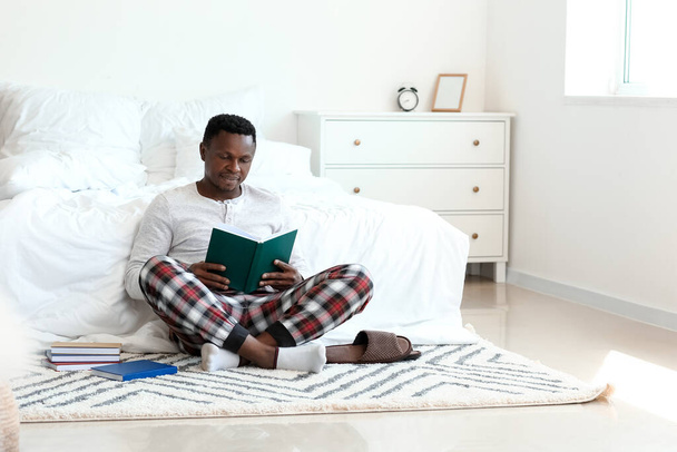 Hombre afroamericano leyendo libro en casa - Foto, imagen