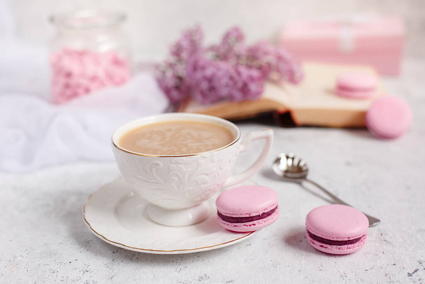 Una taza de café de la mañana, un tazón de lila, macarrones, sobre un fondo claro. Postal buenos días - Foto, Imagen