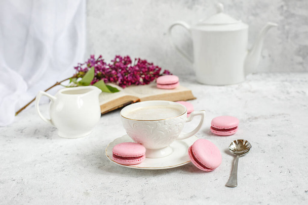 Una taza de café de la mañana, un tazón de lila, macarrones, sobre un fondo claro. Postal buenos días - Foto, Imagen