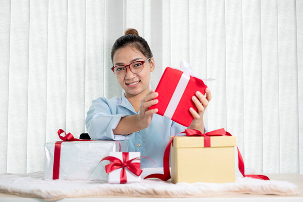 Mulher asiática segurando uma caixa de presente Feliz por ser o doador de surpresa com emoção, alegria e sorrisos nos feriados, Natal, aniversários ou conceito do Dia dos Namorados. - Foto, Imagem