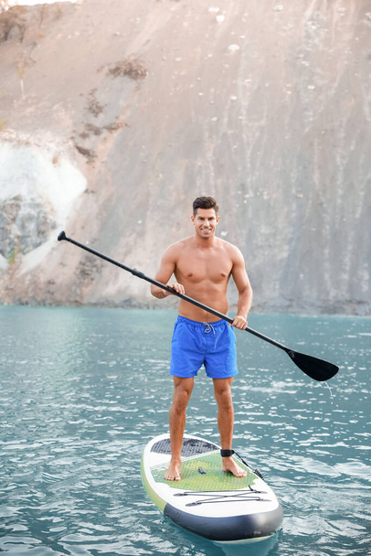 Young man using paddle board for sup surfing in river - Foto, immagini