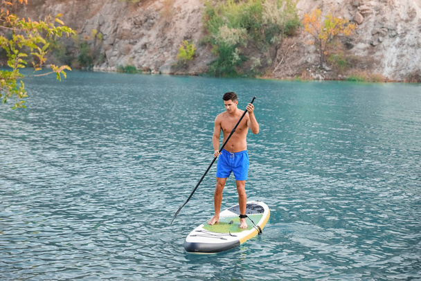 Young man using paddle board for sup surfing in river - Photo, Image