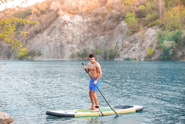 Junger Mann surft mit Paddelbrett im Fluss - Foto, Bild